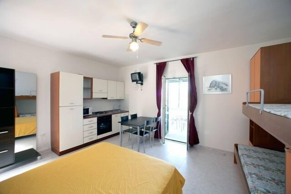 A compact room with a bed, a kitchenette, a dining area, and a balcony.