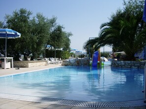Una piscina con sillones de descanso y un tobogán.