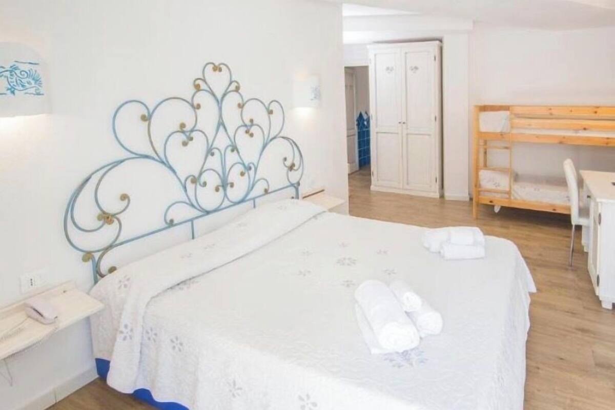 A bedroom with a bed, a desk, and a wardrobe.