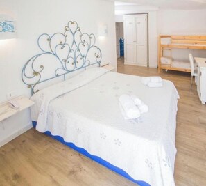 Un dormitorio con cama, escritorio y armario.