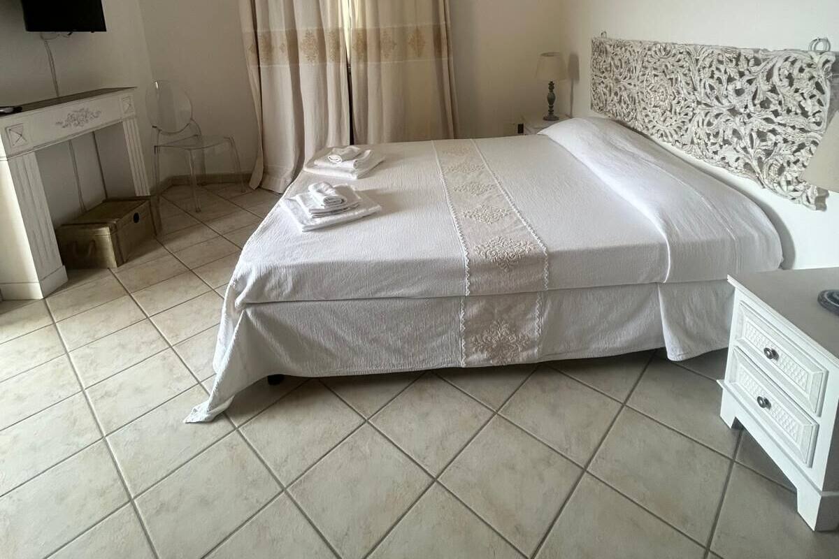 A bedroom with a bed, a desk, a television, and a patterned headboard.
