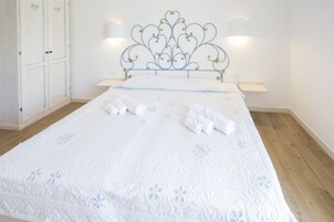 A neatly made bed with a decorative headboard, two bedside tables, and a wardrobe.