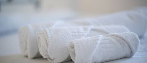 A neatly folded white towel on a bed.