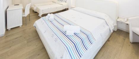 A hotel room with a large bed, two bedside tables, a desk with a chair, a TV, and a wardrobe.