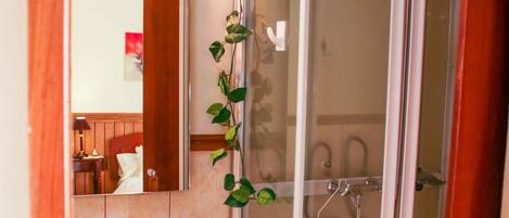 A bathroom with a glass shower enclosure, a sink, and a mirror.
