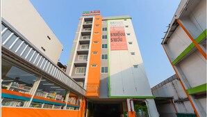 Ein mehrgeschossiges Gebäude mit auffälliger orange-weißer Farbgebung, mit einem großen Schild mit thailändischer Schrift.