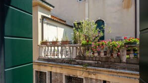 A balcony with potted plants and flowers, a tiled roof, and a brick wall. - Design Palace Apartment by Wonderful Italy (Venice)