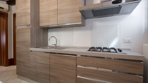 A modern kitchen with wooden cabinetry, a stainless steel range hood, and a gas stove. - Design Palace Apartment by Wonderful Italy (Venice)