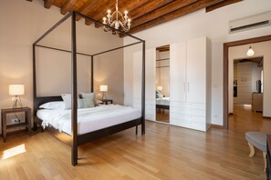 A four-poster bed with a wooden frame, bedside tables with lamps, and a wardrobe with mirrored doors. - Design Palace Apartment by Wonderful Italy (Venice)