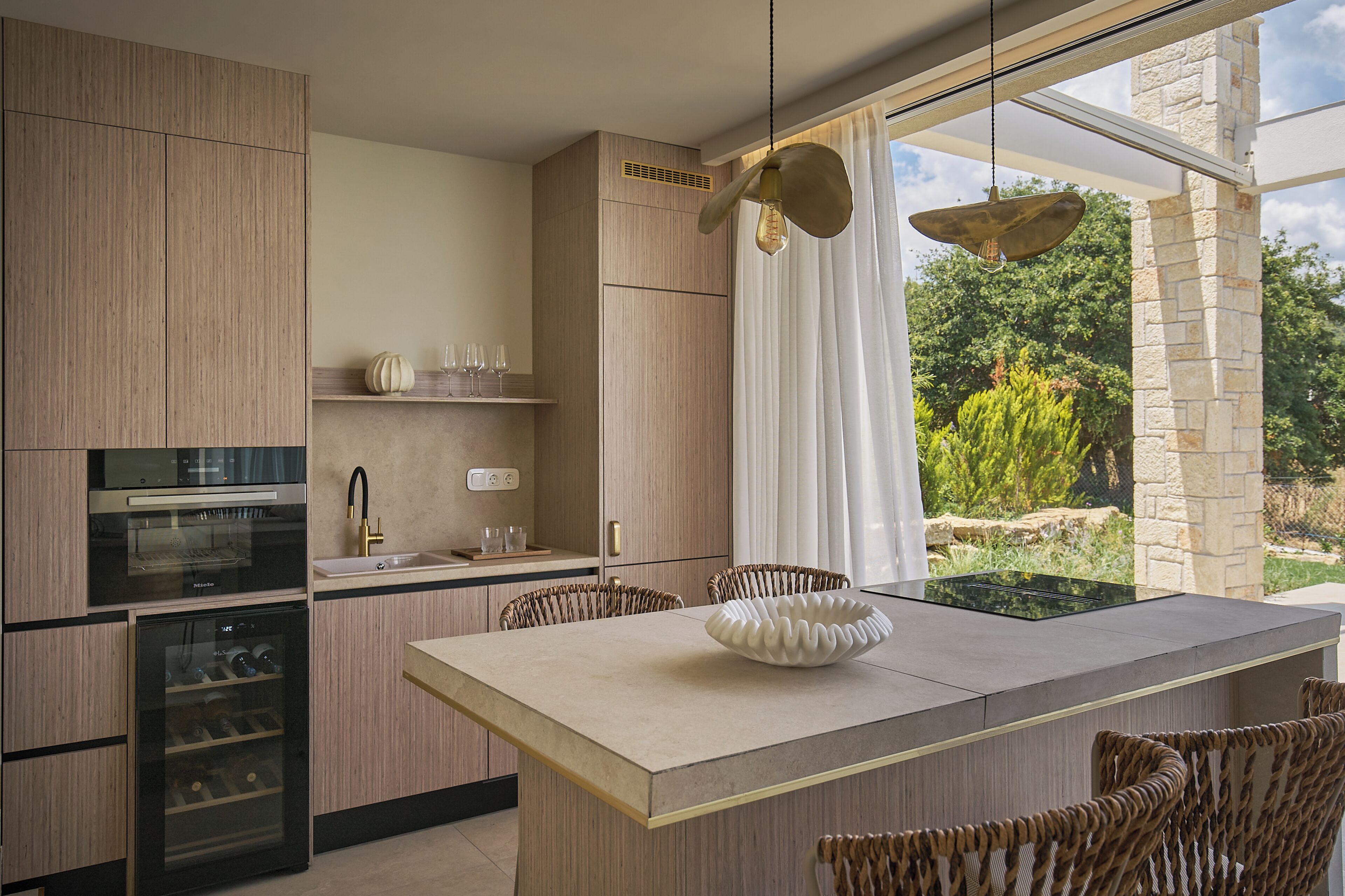 Una cocina moderna con electrodomésticos integrados, un comedor con sillas de mimbre y vistas al exterior.