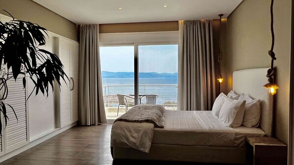 A hotel room with a large bed, a balcony with a view of the sea, and a potted plant. - Kappa Resort (Kassandra)