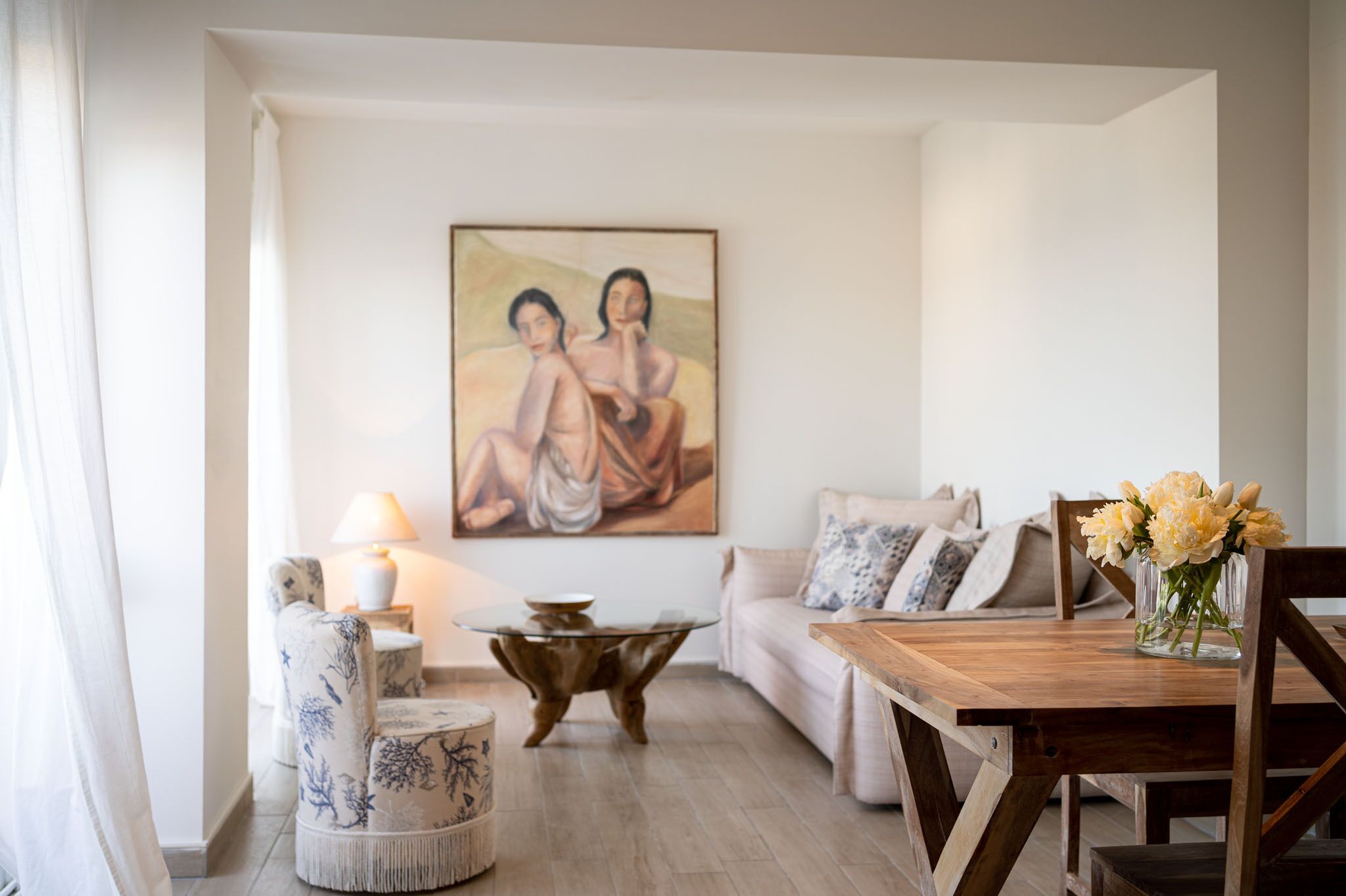 Een woonkamer met een houten eettafel, een bank, een salontafel en een schilderij aan de muur.