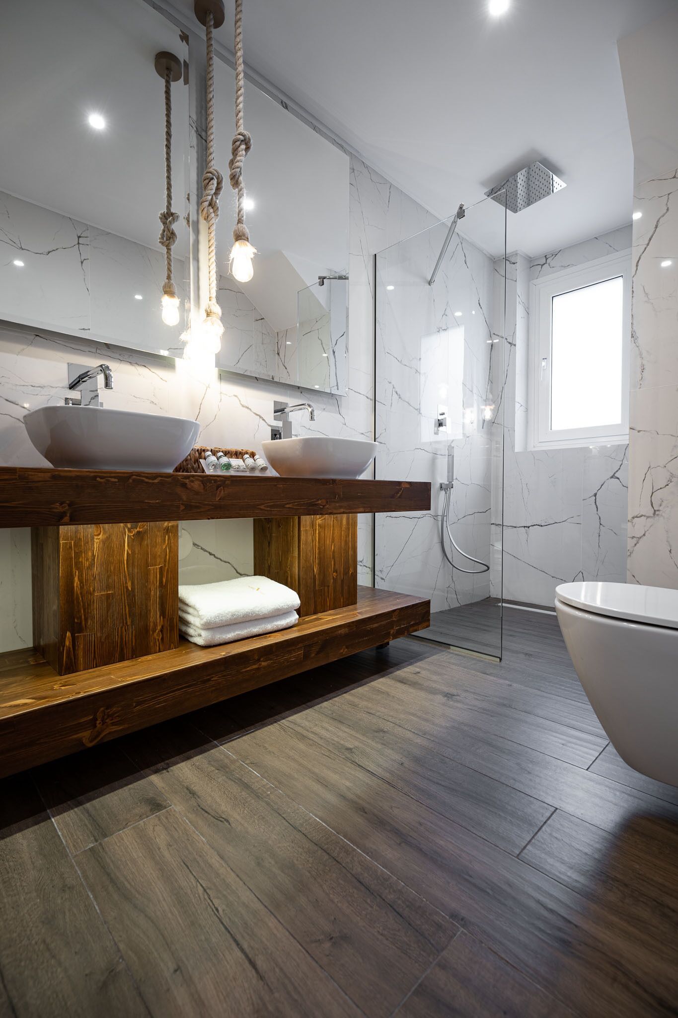Ein modernes Badezimmer mit einem Holzbadezimmer, zwei Waschtüben, einem großen Spiegel und einer begehbaren Dusche.