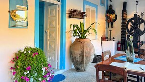 A room with a rustic ceiling, a large potted plant, a mannequin, and a table with chairs. - La Giara Vulcano (Lipari)