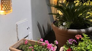 A covered outdoor area with a wooden ceiling, potted plants, and a wall-mounted light fixture. - La Giara Vulcano (Lipari)