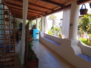 A covered outdoor area with a wooden lattice structure, a blue door, and potted plants. - La Giara Vulcano (Lipari)