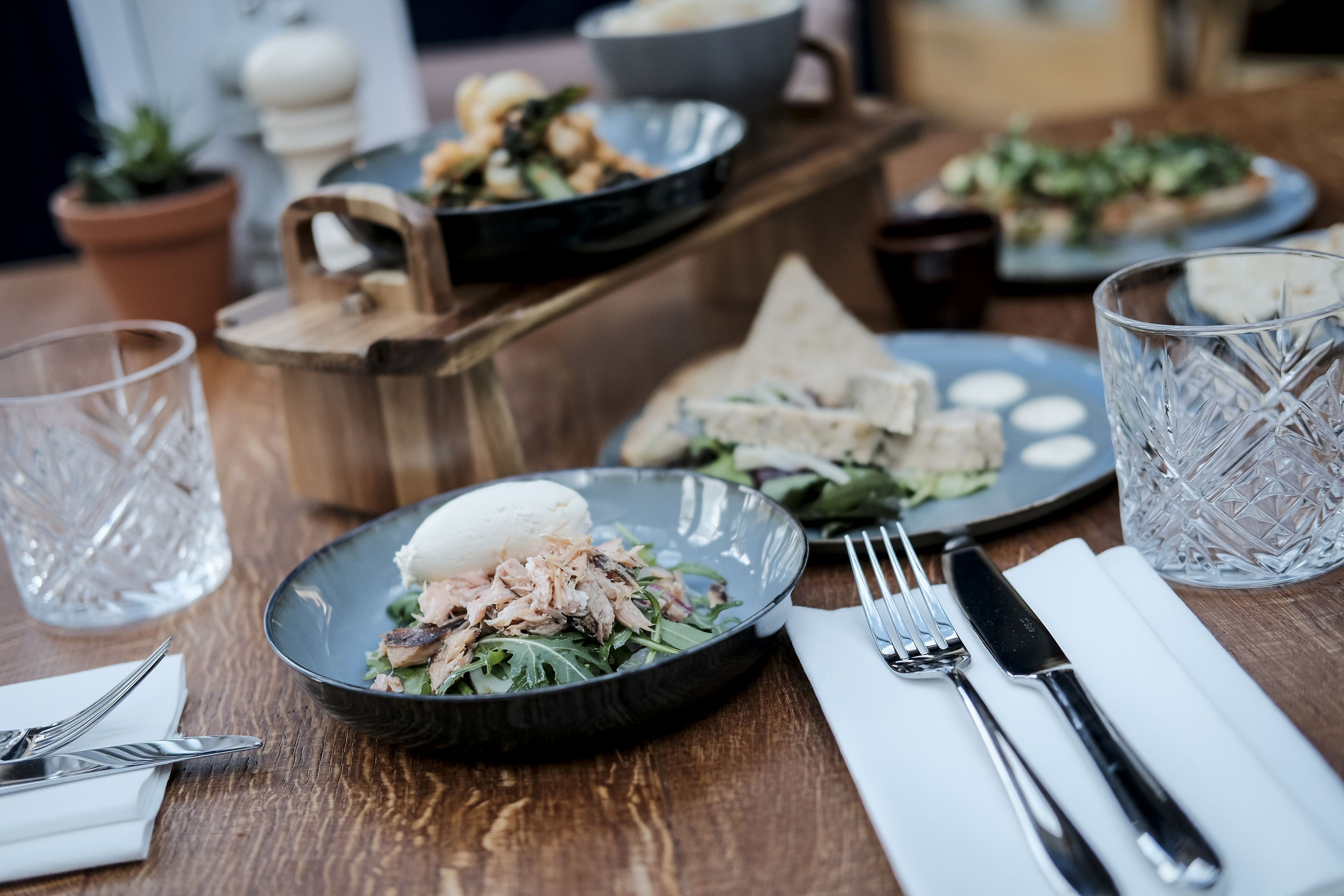 A dining table with plates of food, cutlery, and glasses.