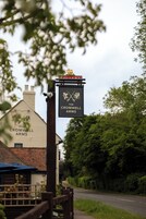 Un letrero de pub para 'The Cromwell Arms' con un diseño tradicional y una cámara montada en un poste.