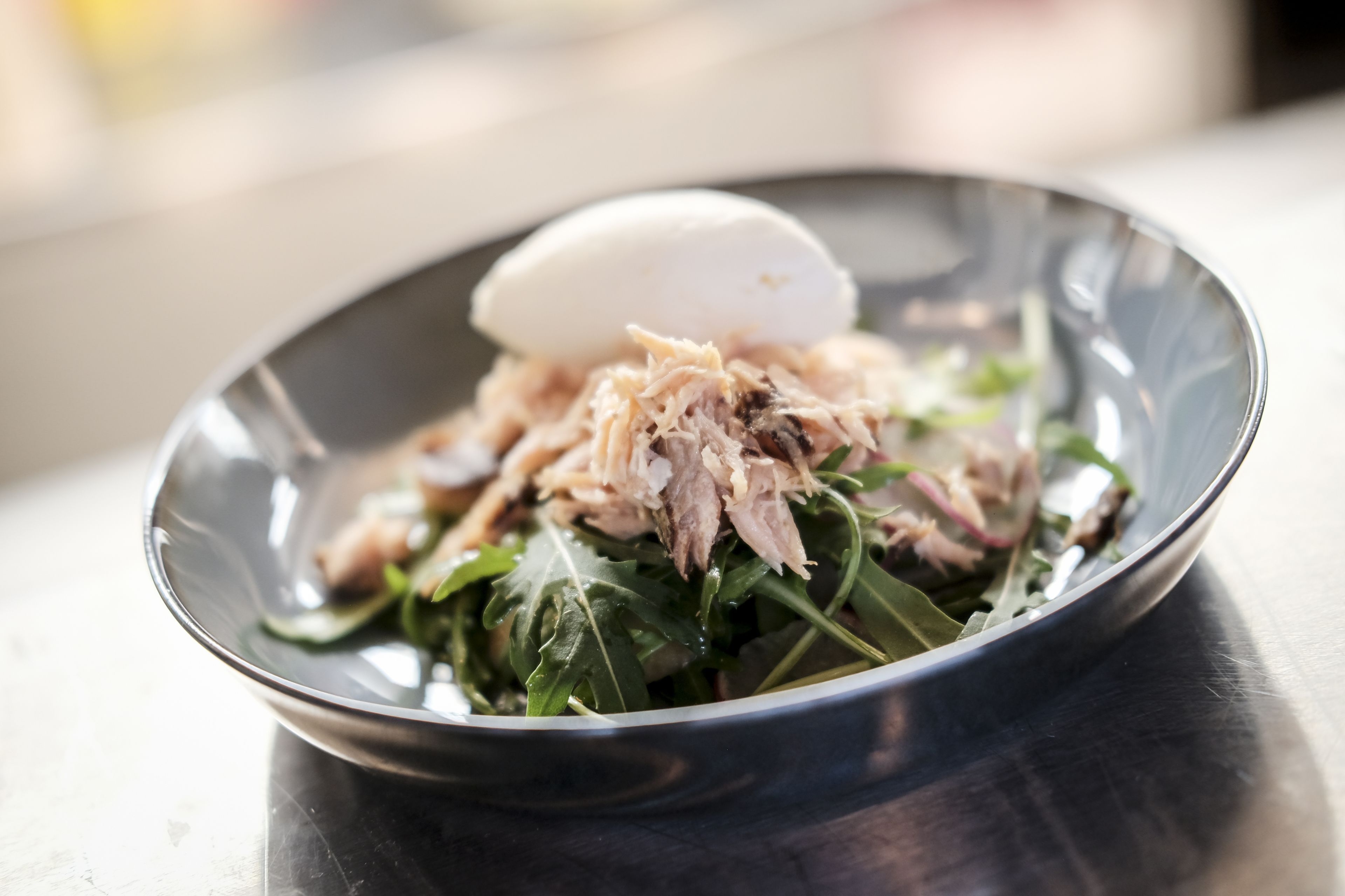 A bowl of food with shredded meat, greens, and a scoop of ice cream.
