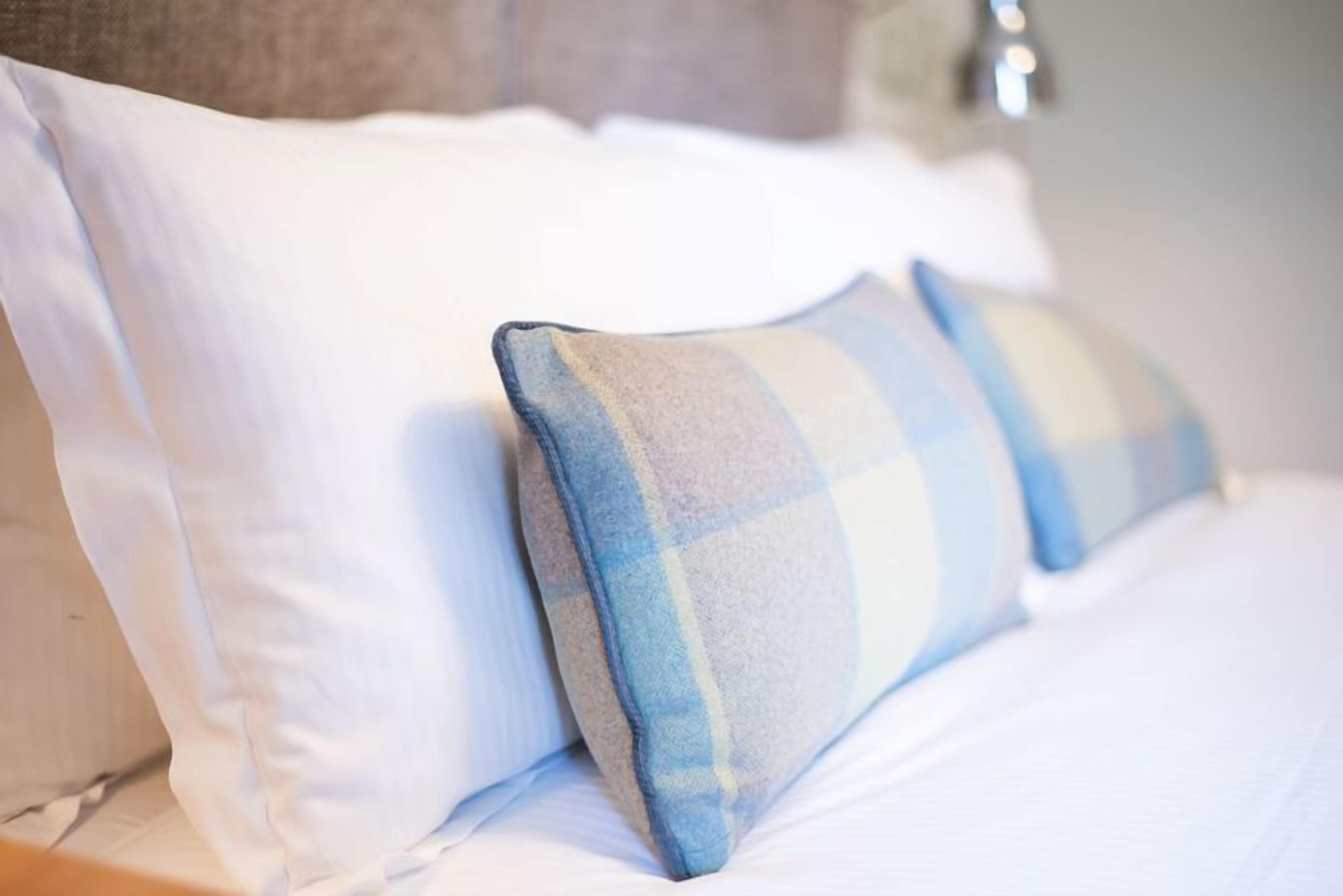 A bed with white and plaid pillows.