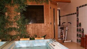 A spa area with a wooden wall, a large bathtub, and exercise equipment. - Hôtel les Mottets (Aussois)