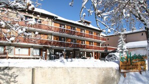 A hotel with a balcony and a sign indicating a restaurant and bar. - Hôtel les Mottets (Aussois)