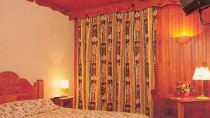 A room with a bed, a desk, a chair, a lamp, and curtains. - Hôtel les Mottets (Aussois)