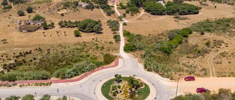 A roundabout with a landscaped island in the center, surrounded by a mix of residential buildings and open fields.