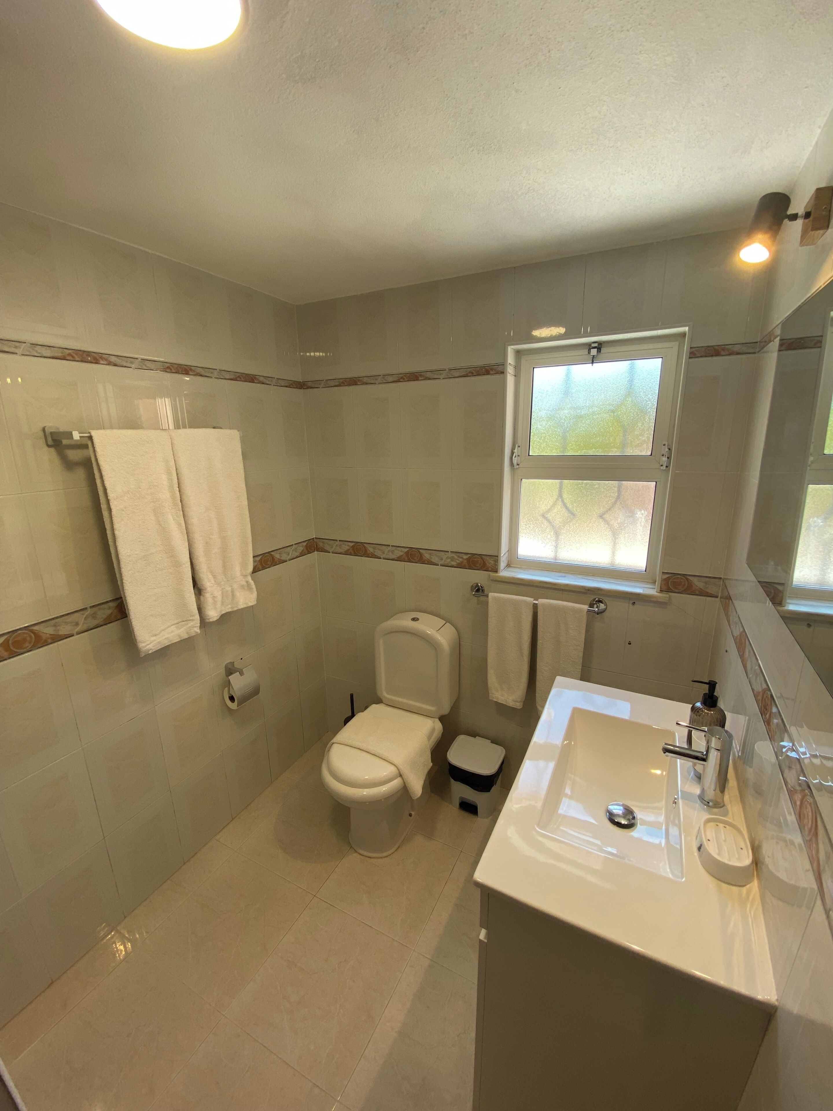 Une salle de bain comprenant des toilettes, un bidet, un lavabo et une fenêtre.