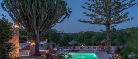 Una piscina al aire libre, sombrillas, sillones reclinables de piscina