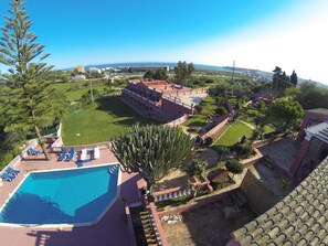 Hotel com piscina, quadra de tênis e vista para o mar.