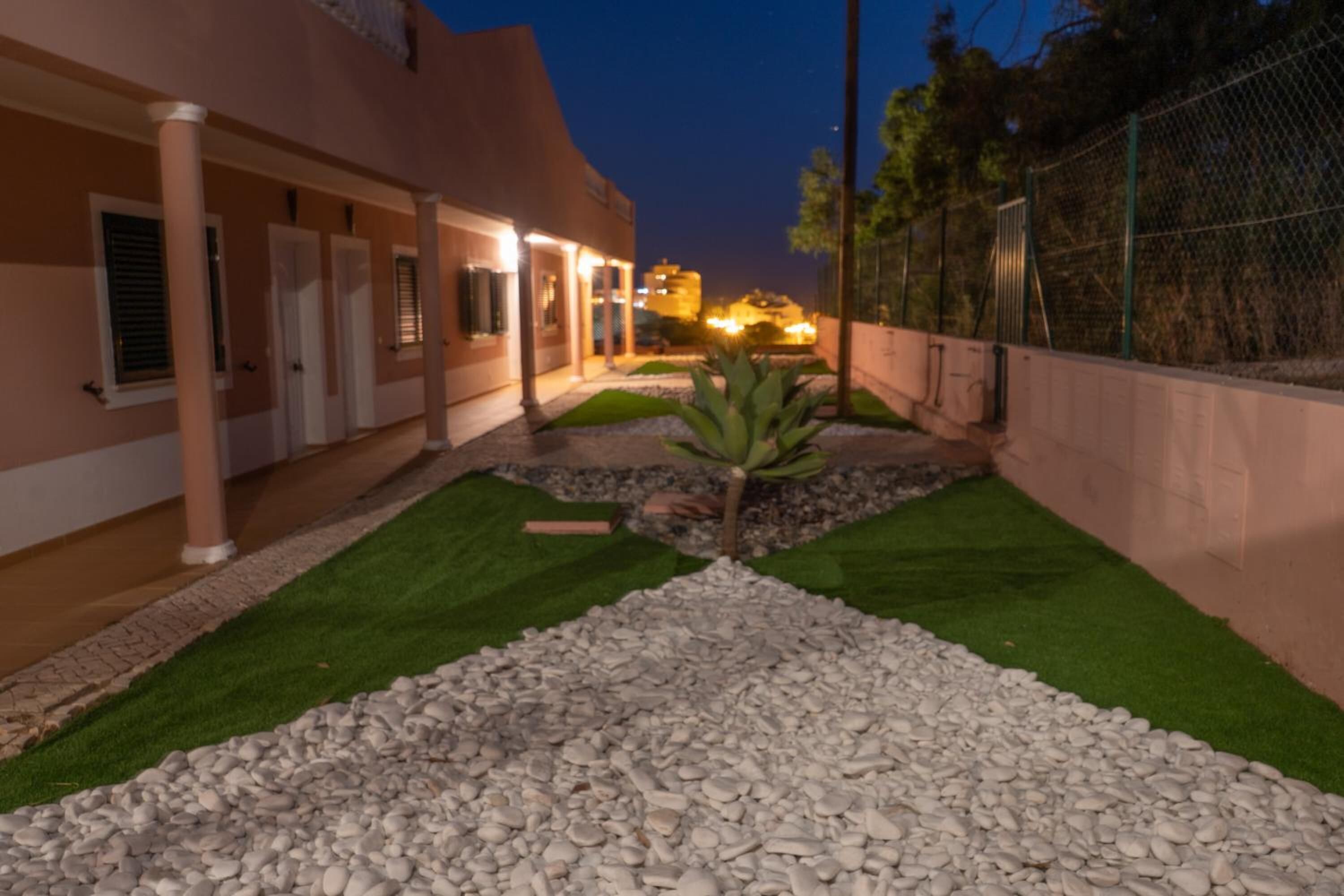 A building with a covered outdoor area, artificial grass, and a small tree.