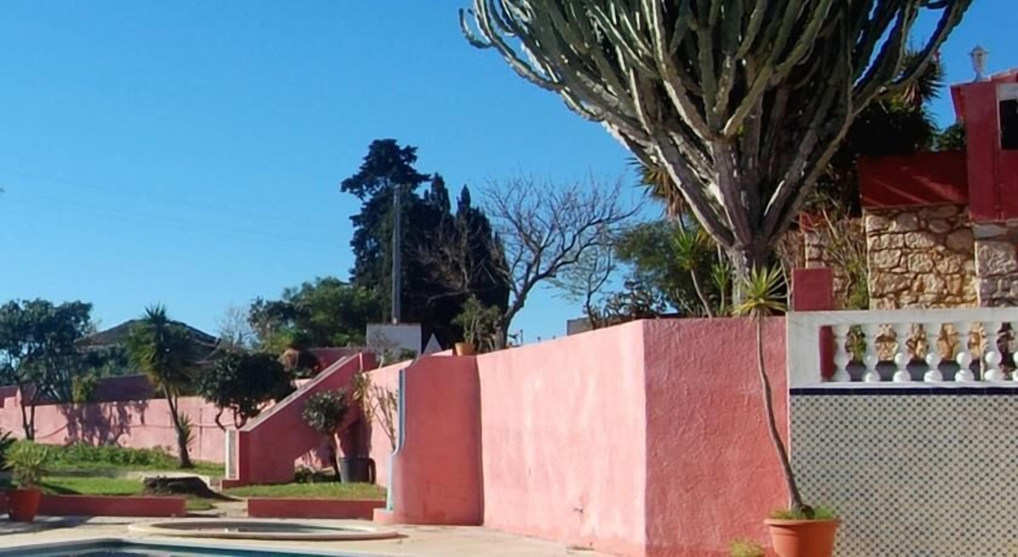 A red building with a staircase leading to a gated entrance.