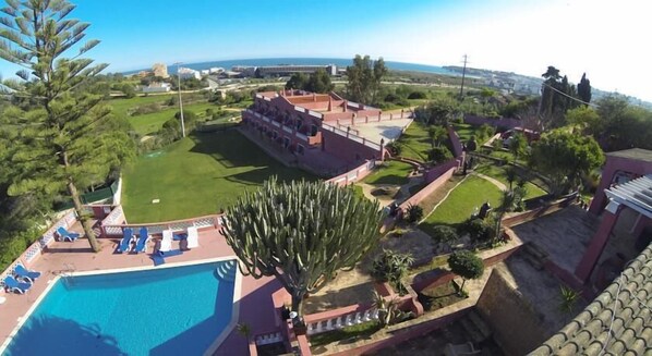 Um resort com piscina, um cacto grande e vista para o oceano.