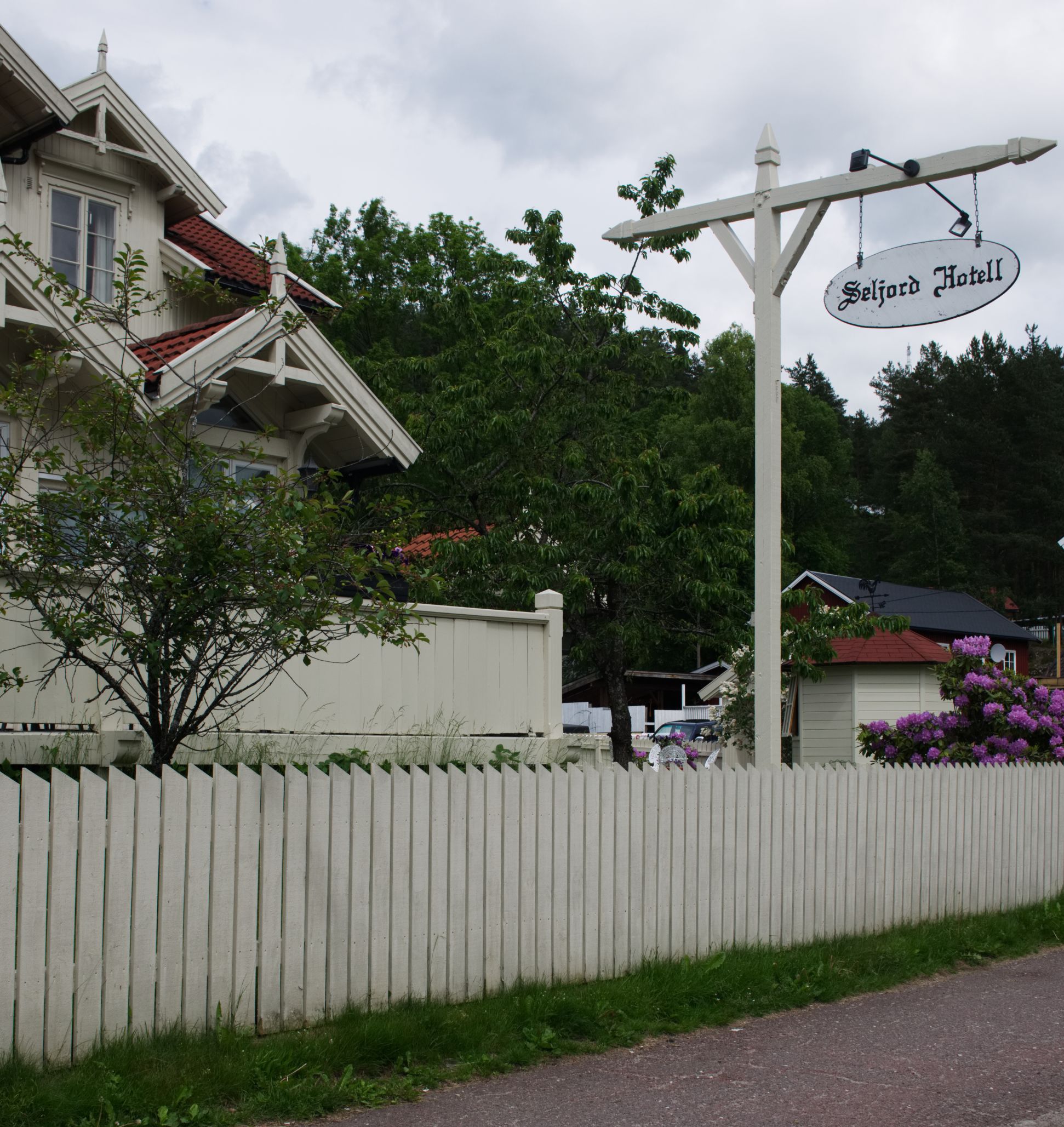 A white picket fence, a building with a red roof, and a sign for Seljord Hotel.