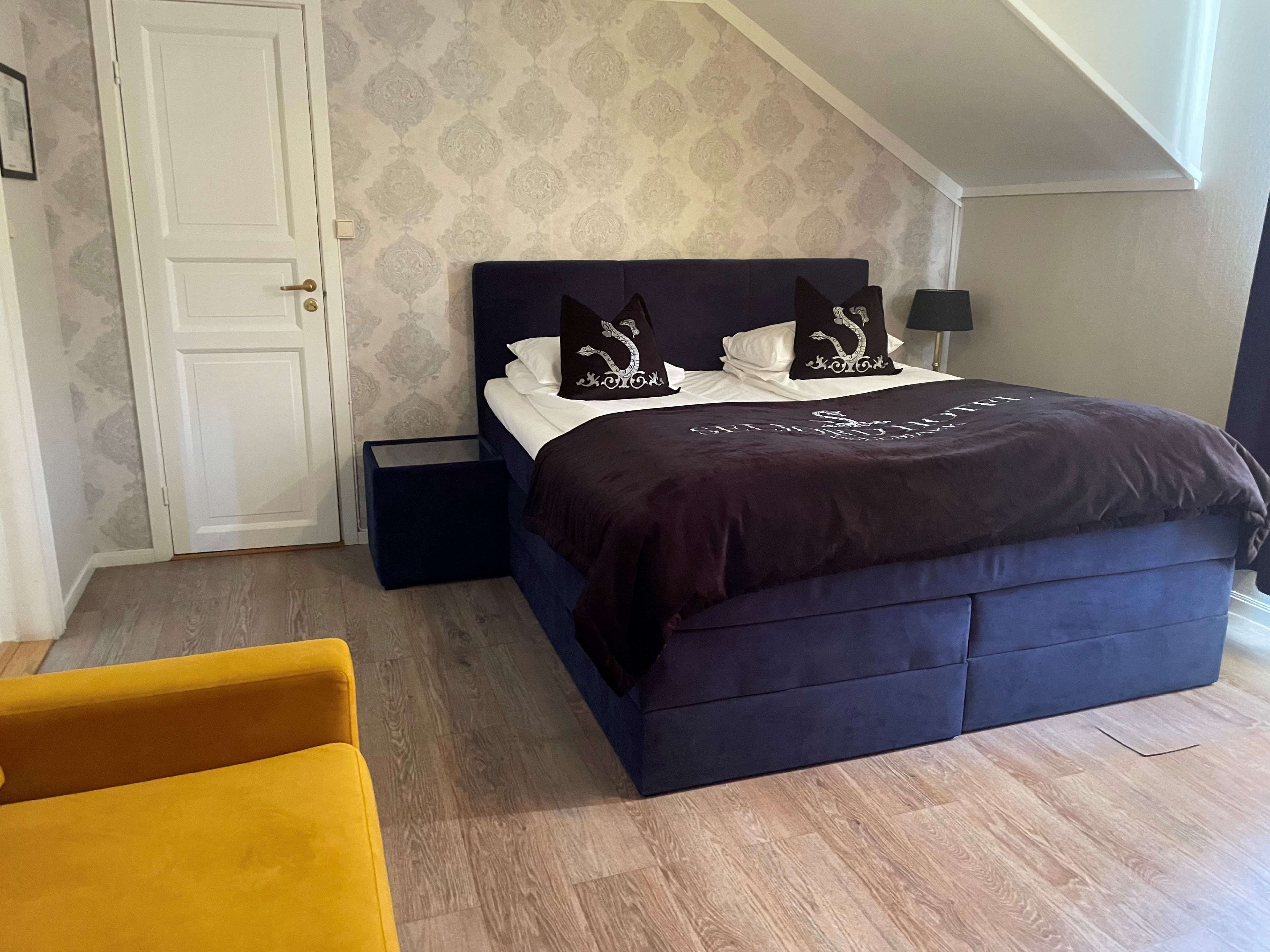 Une chambre à coucher avec un lit, une table de chevet, une chaise et une porte.