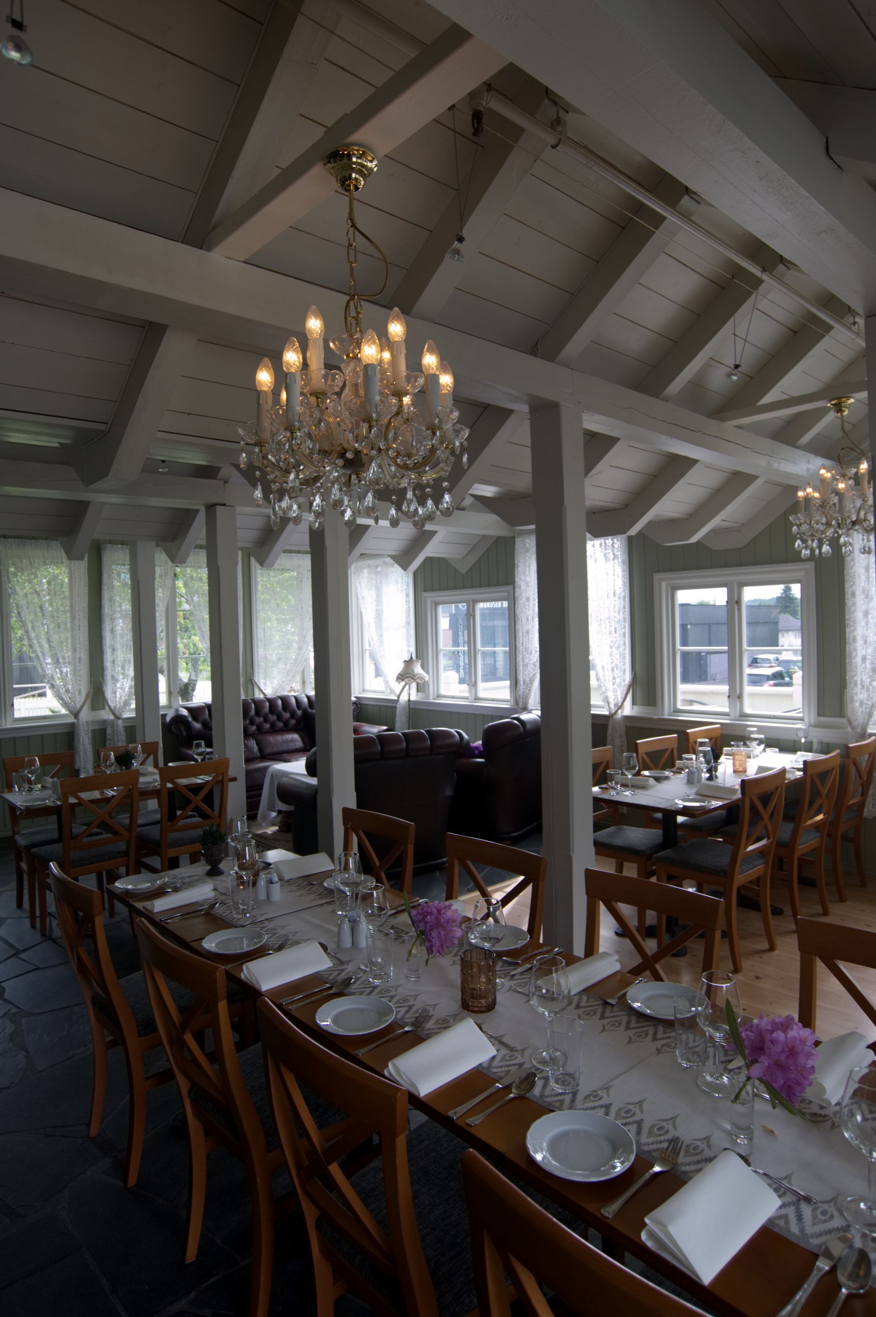 Un comedor con mesas dispuestas para una comida, con candelabros y vistas al exterior.