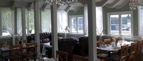 Un comedor con mesas dispuestas para una comida, con candelabros y vistas al exterior.