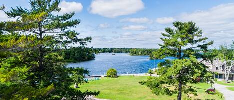 A lakeside property with a grassy lawn, a dock, and a pathway leading to a house.