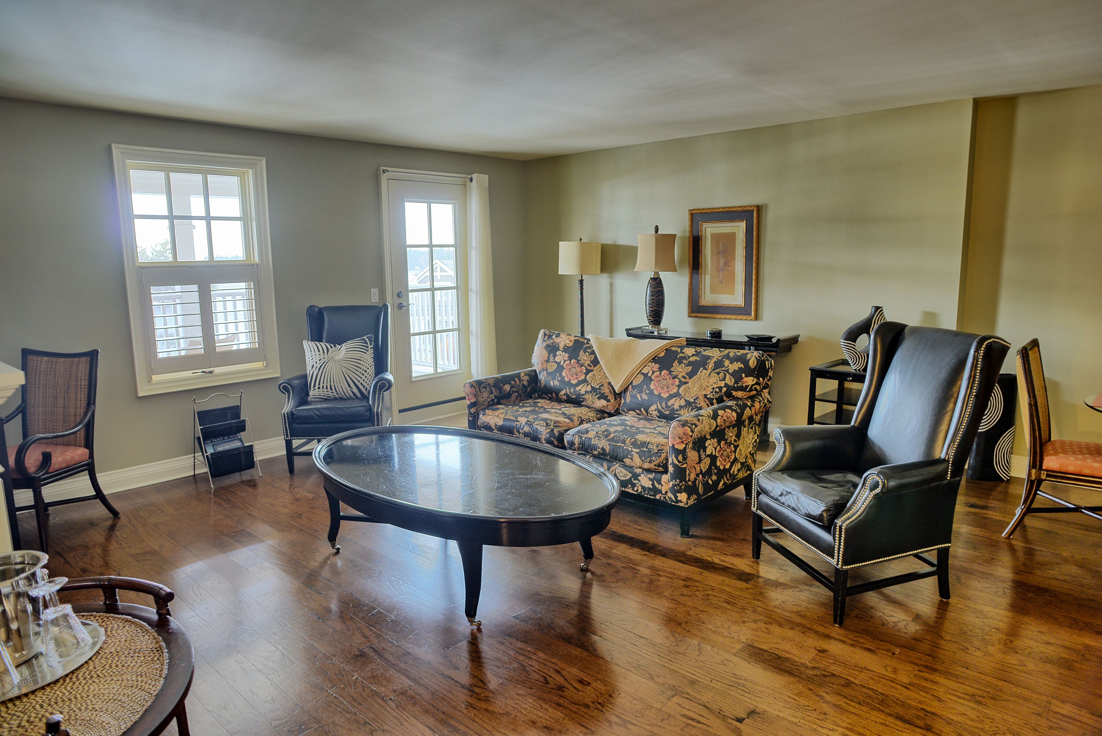A living room with a sofa, armchairs, a coffee table, and a lamp.