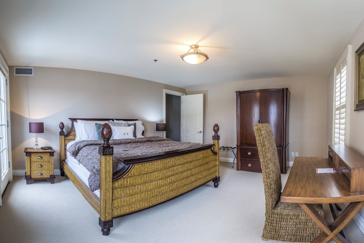A bedroom with a bed, bedside tables, a desk, and a chair.