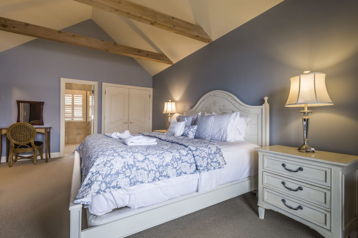 A bedroom with a bed, bedside tables, a chair, and a door.