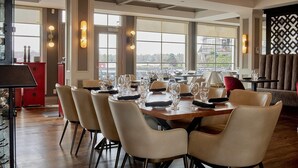 Comedor con una mesa grande dispuesta para varios comensales, sillas y vistas amplias por las ventanas.