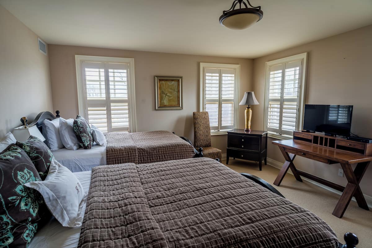 A bedroom with two beds, a desk, a chair, and a television.