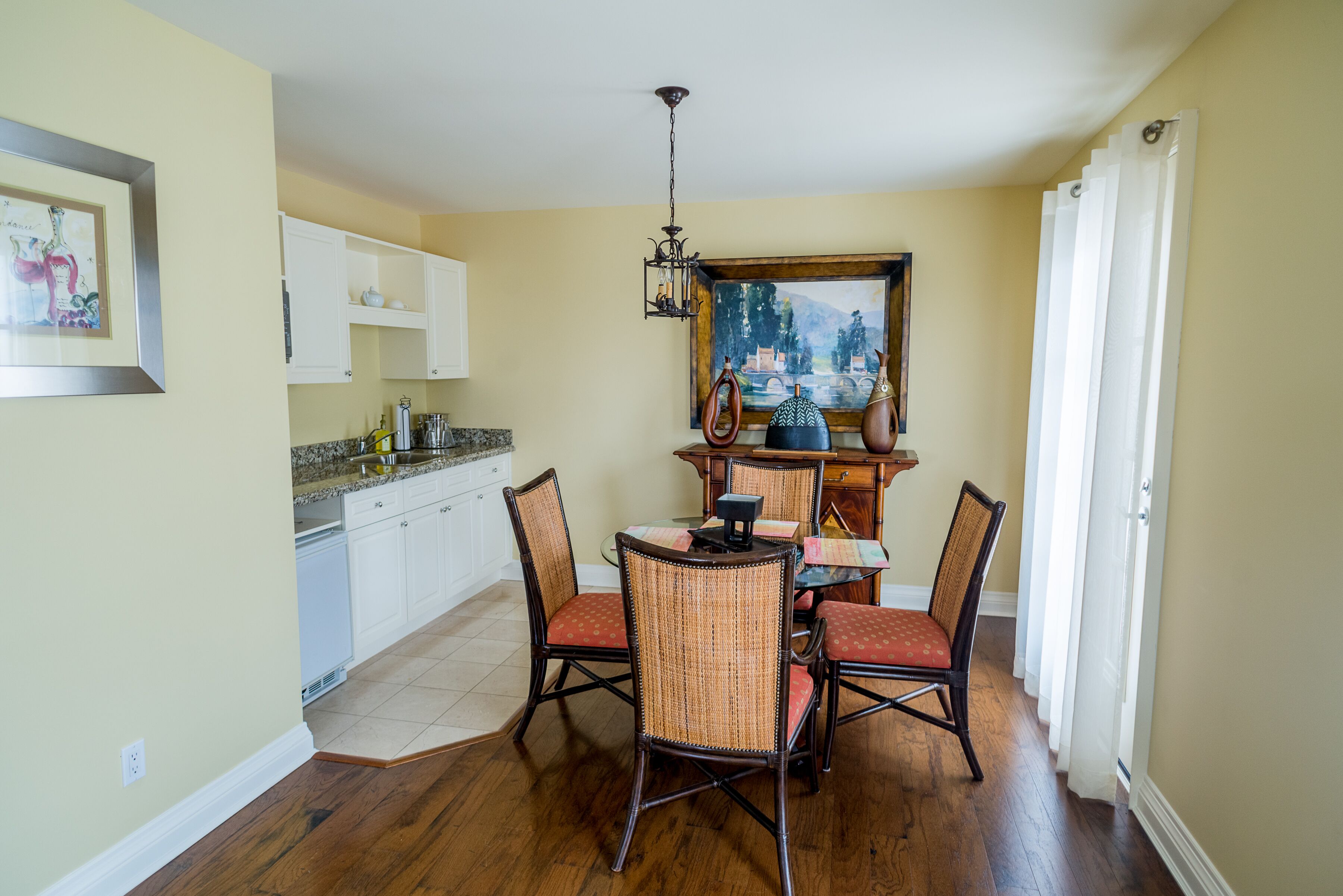 A dining area with a table and chairs, a chandelier, and a painting on the wall.