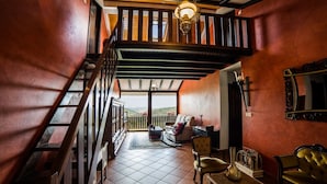 A spacious room with a wooden staircase, a balcony with a view, and a dining area with a table and chairs. - Hotel Rural Fontequeiroso (Muxía)
