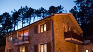 A stone building with multiple windows and balconies, surrounded by trees. - Hotel Rural Fontequeiroso (Muxía)