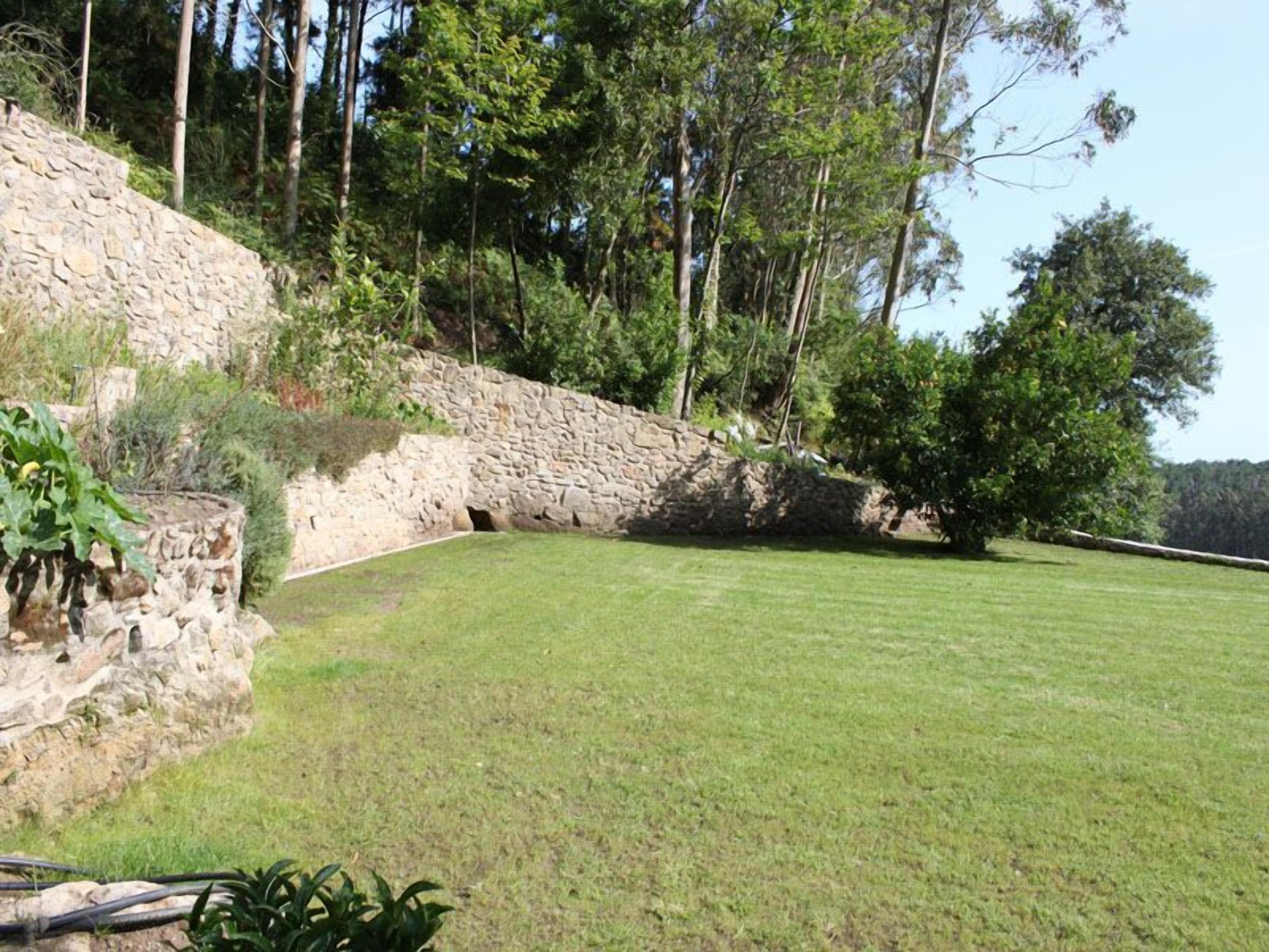 A stone retaining wall with a grassy area in front.