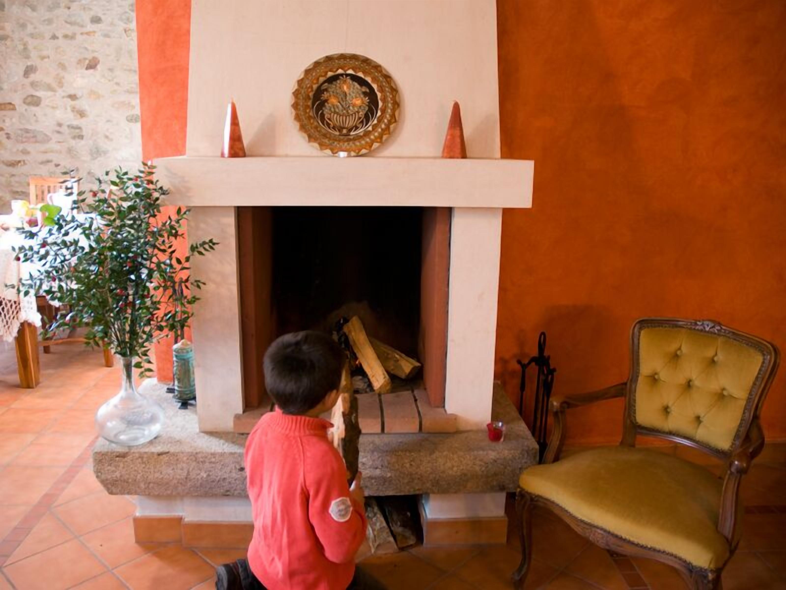 Un niño jugando con un juguete cerca de una chimenea con un plato decorativo encima.