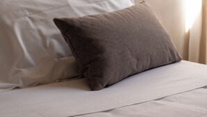 A neatly made bed with white and gray bedding, a wooden headboard, and a window with curtains. - Hotel Mediterraneo (Lavagna)